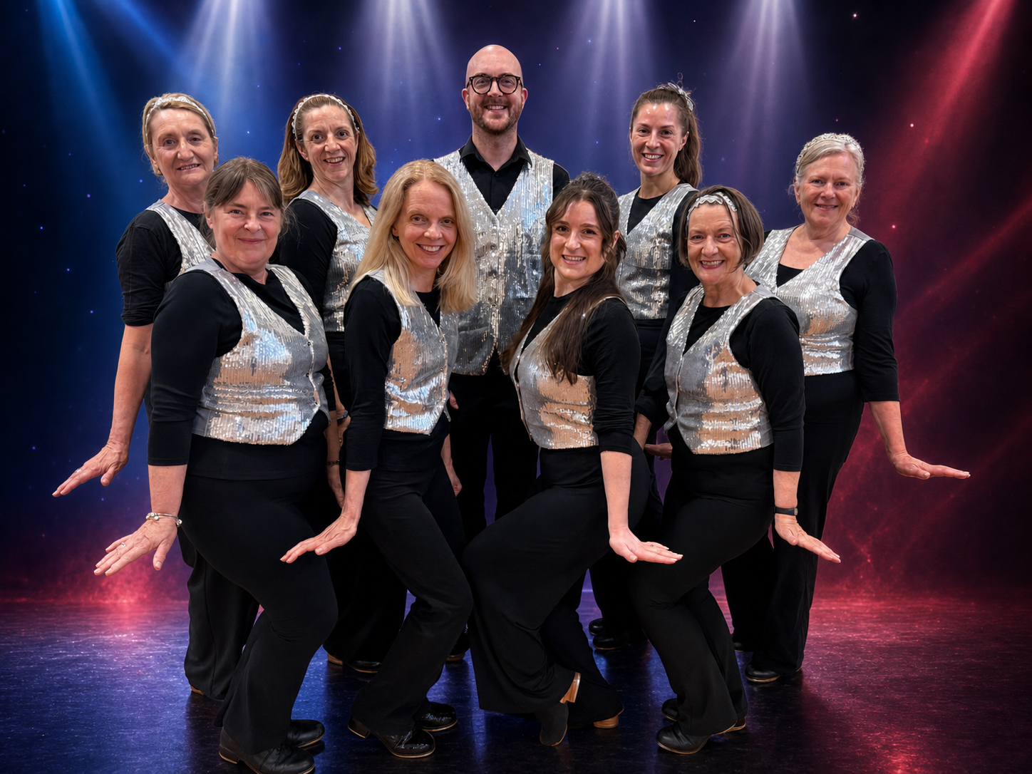 Adult tap dancers in silver sequin waistcoats under stage spotlights